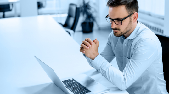 Successful young businessman working on laptop at workplace